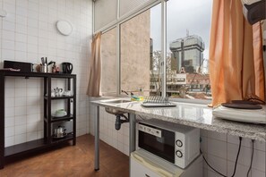 Keittiössä on ikkuna, pesuallas, liesi ja hylly, jossa on keittiötarvikkeita.