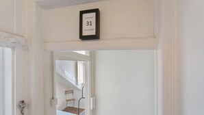 Ein Flur mit einer Tür, auf der '31' steht, die zu einem Zimmer mit einem Bett und einem Fenster führt.