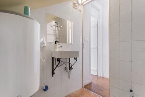 Un baño con lavamanos blanco, espejo y ducha.