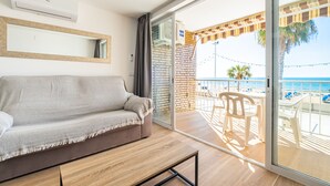Ein Balkon mit Meerblick, einer Couch und einem Tisch mit Stühlen.