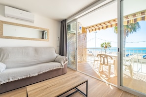 Un balcon avec vue sur la mer, un canapé et une table avec des chaises.