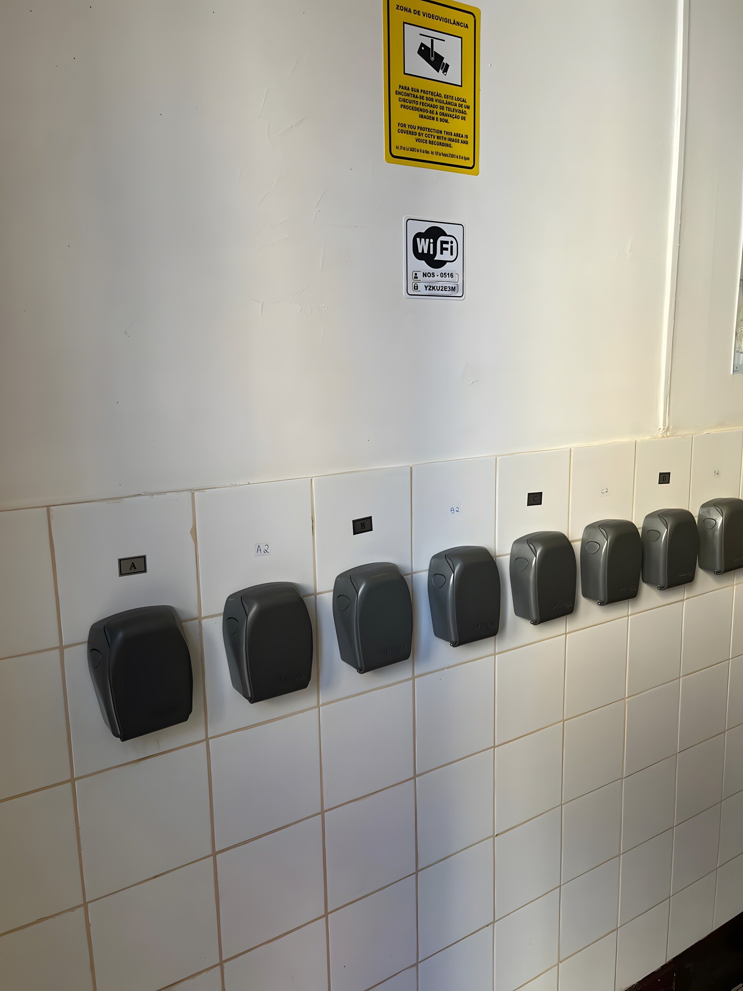 A wall with hand sanitizer dispensers, a Wi-Fi sign, and a warning sign.