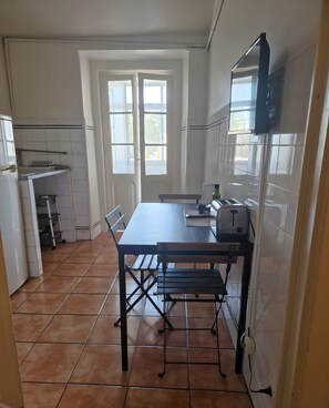 Una cocina con una mesa, sillas, un tostador y un refrigerador.