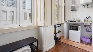 A compact kitchen with a window, a microwave, a small refrigerator, and a sink. - Studio Apartment '21 - Amoreiras Apartments' with Wi-Fi (Lisboa)