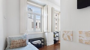 A bedroom with a bed, a window, a small table, and a wall-mounted TV. - Studio Apartment '21 - Amoreiras Apartments' with Wi-Fi (Lisboa)
