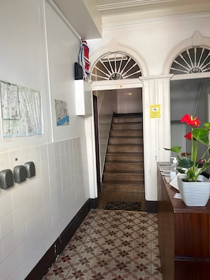 A hallway with a tiled floor, a staircase, and a wall-mounted hand sanitizer dispenser. - Apartment '33 - Amoreiras Apartments' with Wi-Fi (Lisboa)