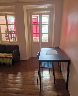 A room with a wooden floor, a table with a chair, a sofa, and a door with windows. - Apartment '33 - Amoreiras Apartments' with Wi-Fi (Lisboa)