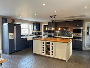 A modern kitchen with a central island, built-in appliances, and pendant lighting.