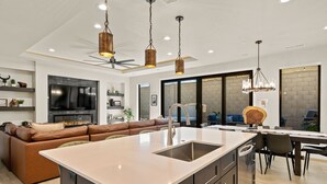 A modern kitchen with a central island, a dining area with chairs, a sofa, and a fireplace. - Horseman's Hideout 3 Bedroom Townhouse (Hurricane)