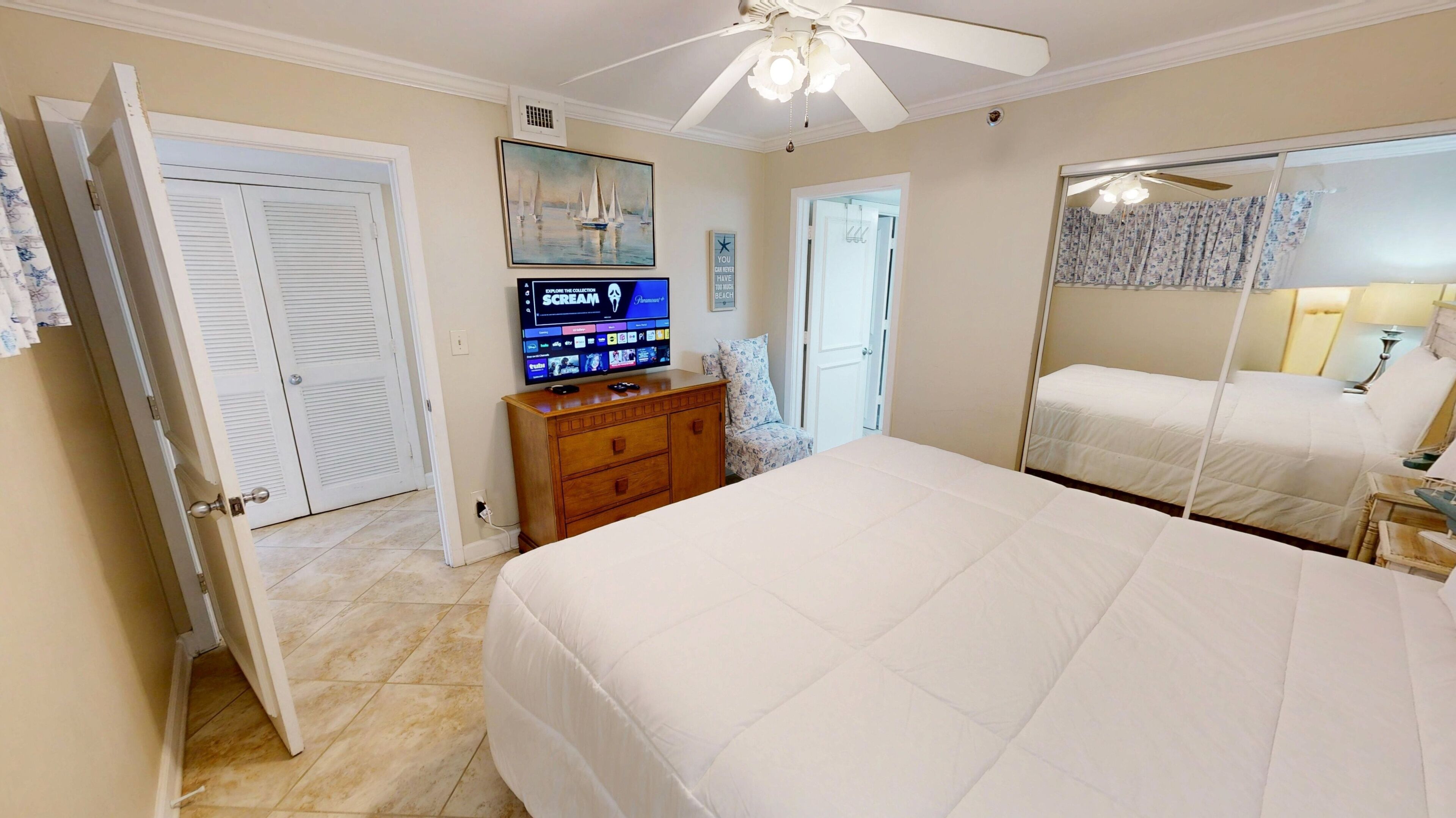 A bedroom with a bed, a dresser, a television, and a door.