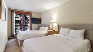 A hotel room with two beds, a television, a lamp, and a balcony with a view of trees. - Fp219 Foxpine 1br 2 Ba 1 Bedroom Condo (Copper Mountain)