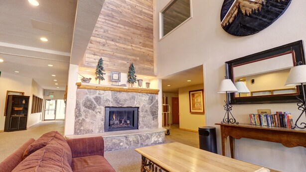 A spacious living area with a fireplace, a sofa, a wooden table, and a bookshelf. - Fp219 Foxpine 1br 2 Ba 1 Bedroom Condo (Copper Mountain)