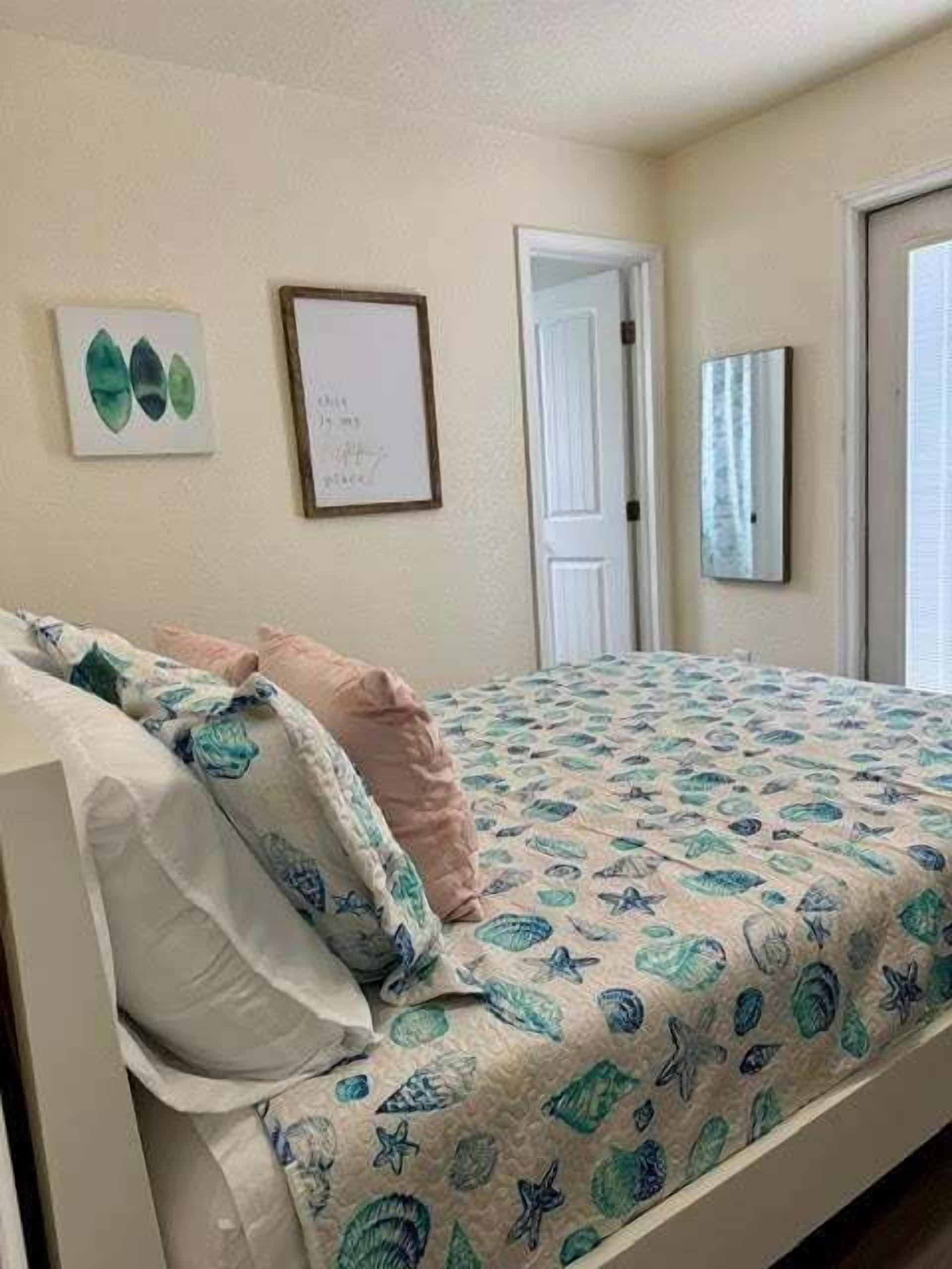 Une chambre à coucher avec un lit, une porte et deux objets encadrés accrochés au mur.