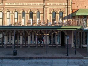 Ein Gebäude mit Bogenfenstern und einem Balkon mit Außenbestuhlung.
