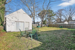 A small shed with a door and windows, a table with chairs, and a fenced yard with trees. - Cozy Cradock Charm Your Portsmouth Home Base 4 Bedroom Home (Portsmouth)