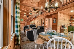 A cabin interior with a dining area, a sofa, a staircase, and a kitchen area. - Shamrock Valley 1 Bedroom Cabin (Sevierville)