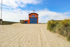 A coastal building with a blue door, a flag, and a sign reading 'National Coastwatch'. - Chalet 62 (Great Yarmouth)
