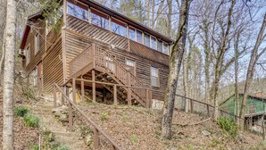 A wooden cabin with a staircase leading to a deck, surrounded by trees. - Private Hot Tub! Hillside Smokies Base Camp (Townsend)