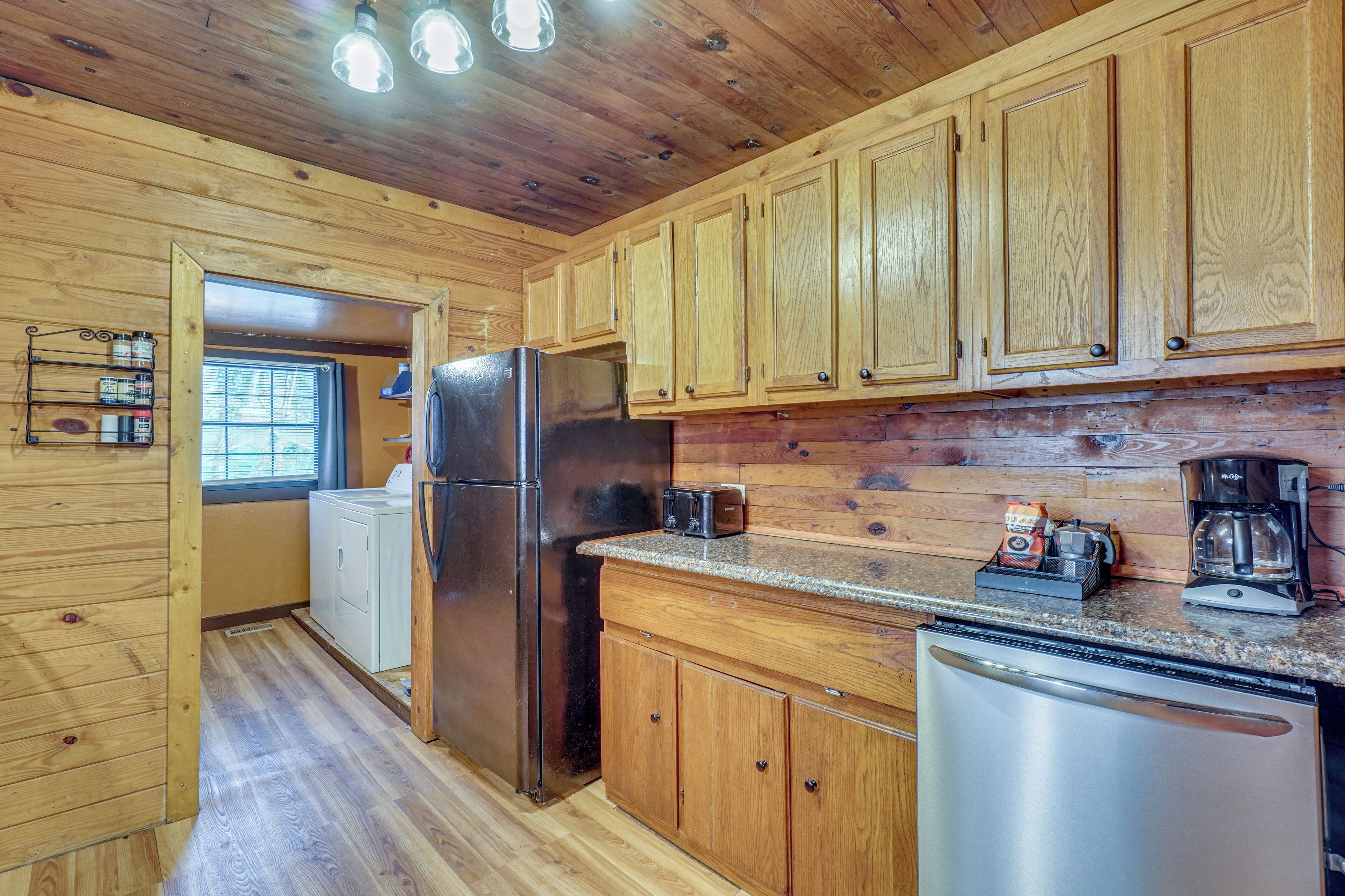 A wooden-paneled kitchen with a refrigerator, dishwasher, and coffee maker.