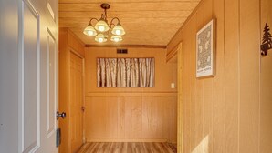 A hallway with wooden walls, a ceiling light fixture, a door, and a framed artwork on the wall. - Private Hot Tub! Hillside Smokies Base Camp (Townsend)