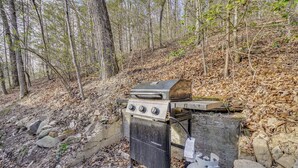 A portable gas grill with a side burner, a propane tank, and a metal cart. - Private Hot Tub! Hillside Smokies Base Camp (Townsend)