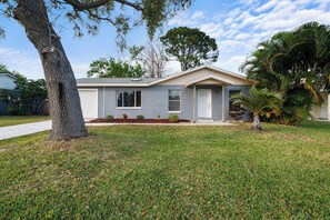A residential house with a front yard, a driveway, and a palm tree. - Pet-friendly Melbourne Retreat w/ Lanai & Hammock! (Melbourne)