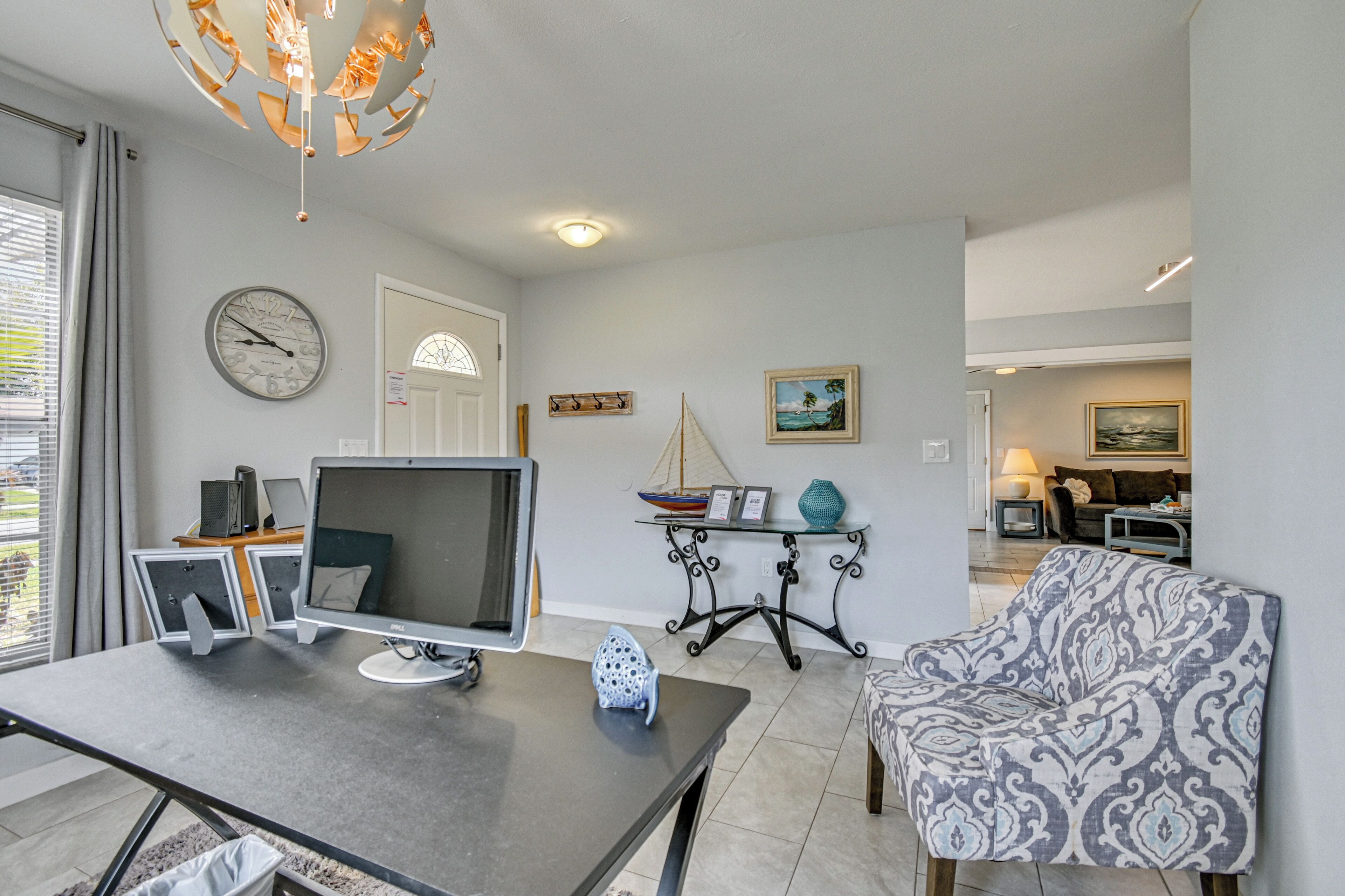 A modern living room with a desk, computer, decorative items, and a patterned armchair.