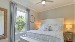 A bedroom with a large bed, a ceiling fan, a window with curtains, a bedside table with a lamp, and a wall decoration. - < 1 Mi to Beach: 30A Escape w/ Bikes + Pool Access (Santa Rosa Beach)