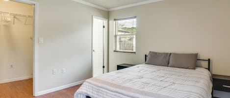 A bedroom with a bed, a ceiling fan, a window with blinds, and a door leading to a closet.