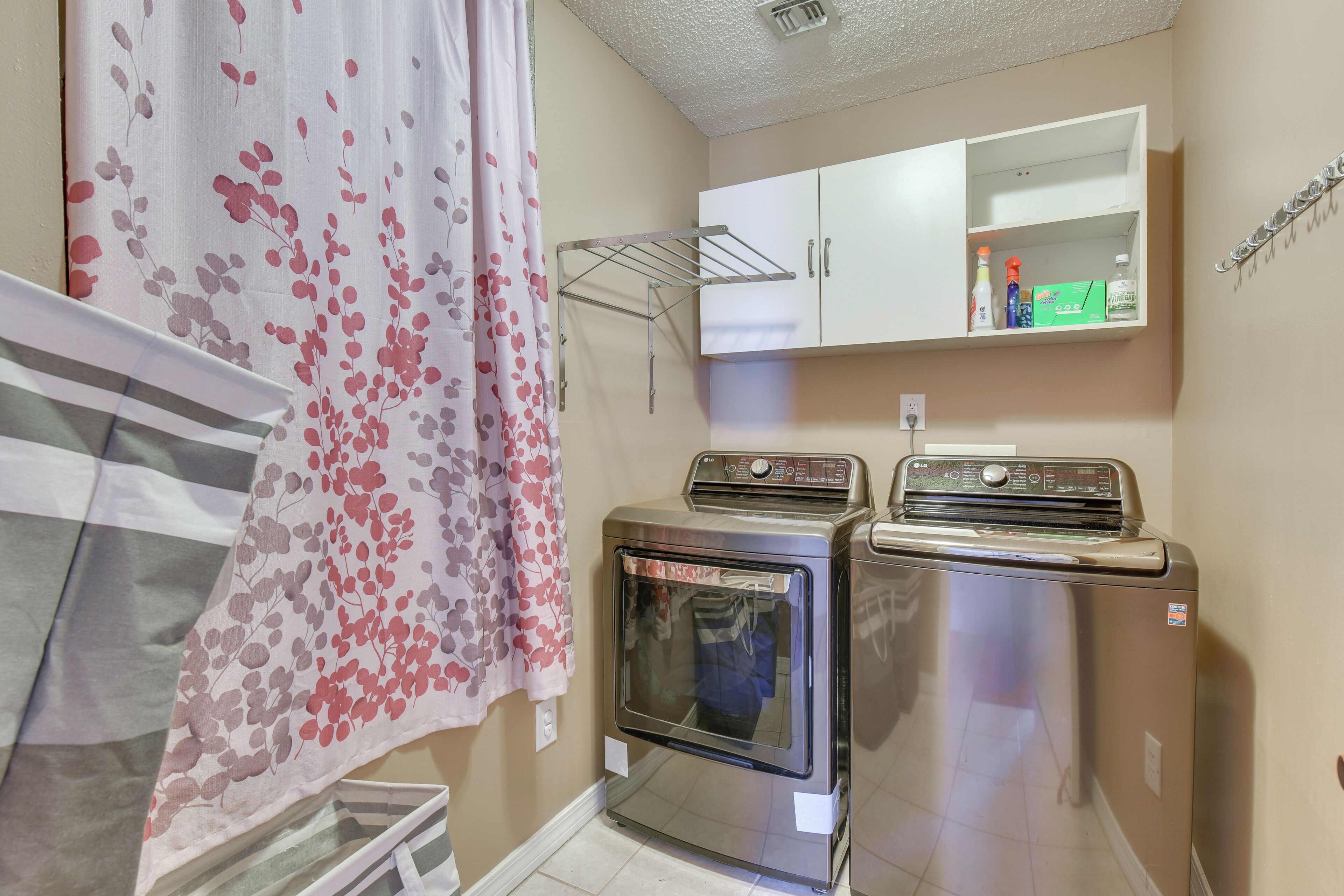 A laundry area with a dryer, a washing machine, and a cabinet above.