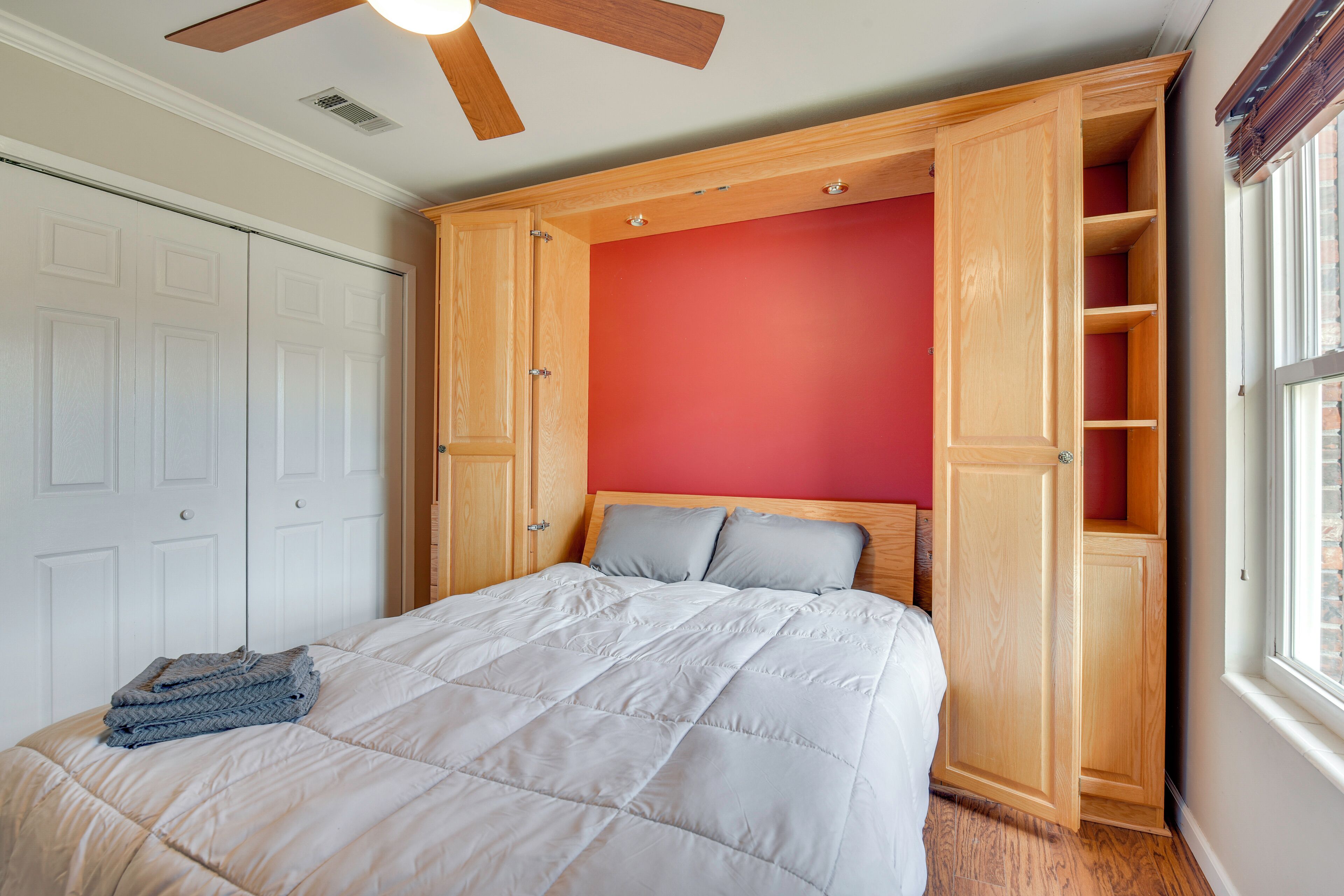 Une chambre à coucher avec un lit, un ventilateur de plafond, une armoire et une fenêtre.