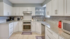 A modern kitchen with white cabinets, granite countertops, a stainless steel range hood, and a built-in oven. - 4 Mi to Garniers Beach Park: Home w/ Private Pool! (Fort Walton Beach)