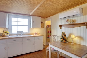 A kitchen with wooden cabinets, a sink, a window, an air conditioner, a small Christmas tree, and a table with a lamp. - 'farm House at Fairview' Rustic Retreat in Amherst (Amherst)