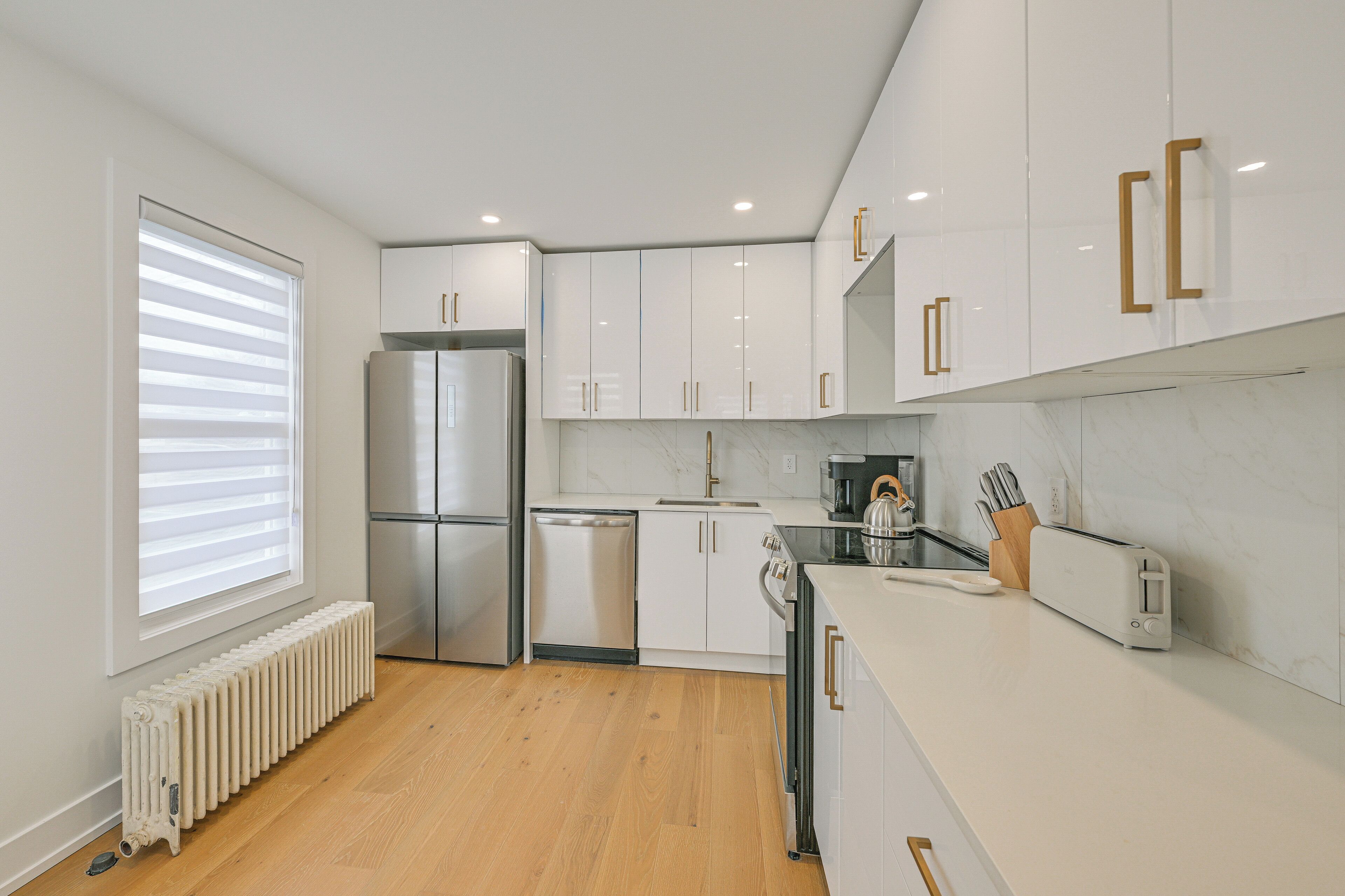 A modern kitchen with white cabinetry, a built-in oven, and a toaster.