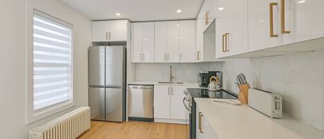 A modern kitchen with white cabinetry, a built-in oven, and a toaster.