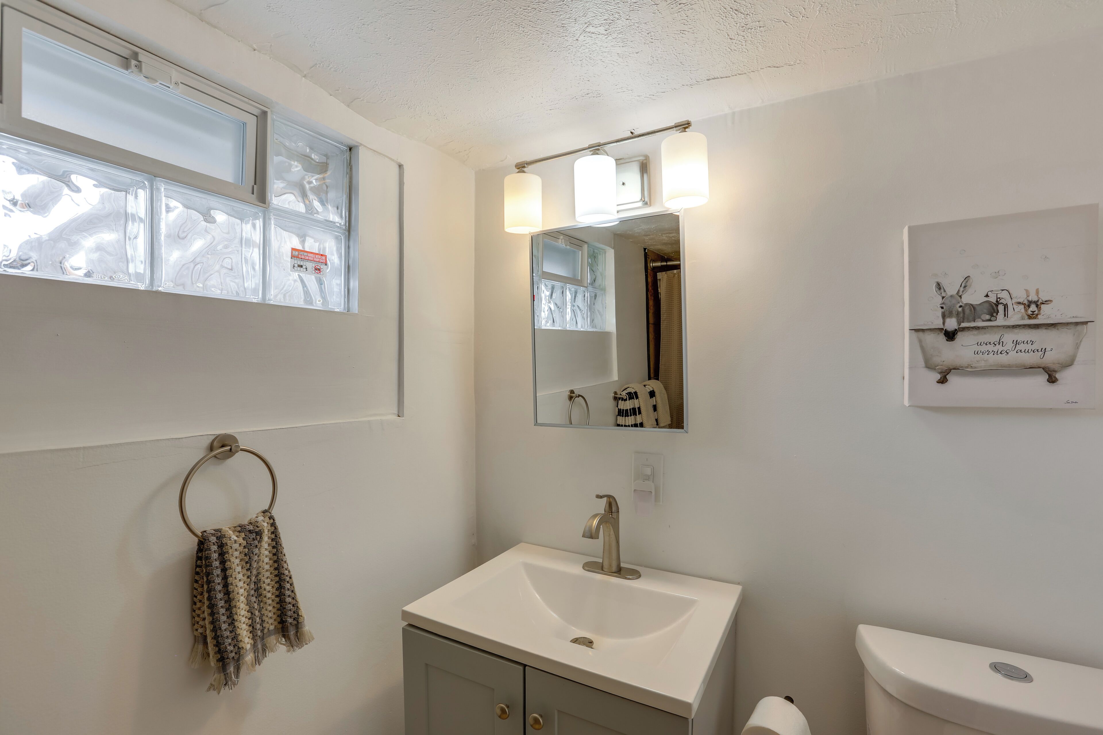 A bathroom with a sink, mirror, and toilet.
