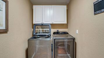 A laundry area with two washers and dryers, white cabinets above, and a sign on the wall.
