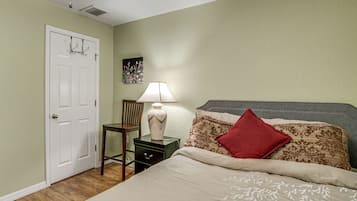 A bedroom with a bed, a nightstand, a lamp, a chair, and a door.