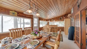 Ein Holzinterieur mit einem für vier Personen gedeckten Esstisch, Stühlen und einem großen Fenster.