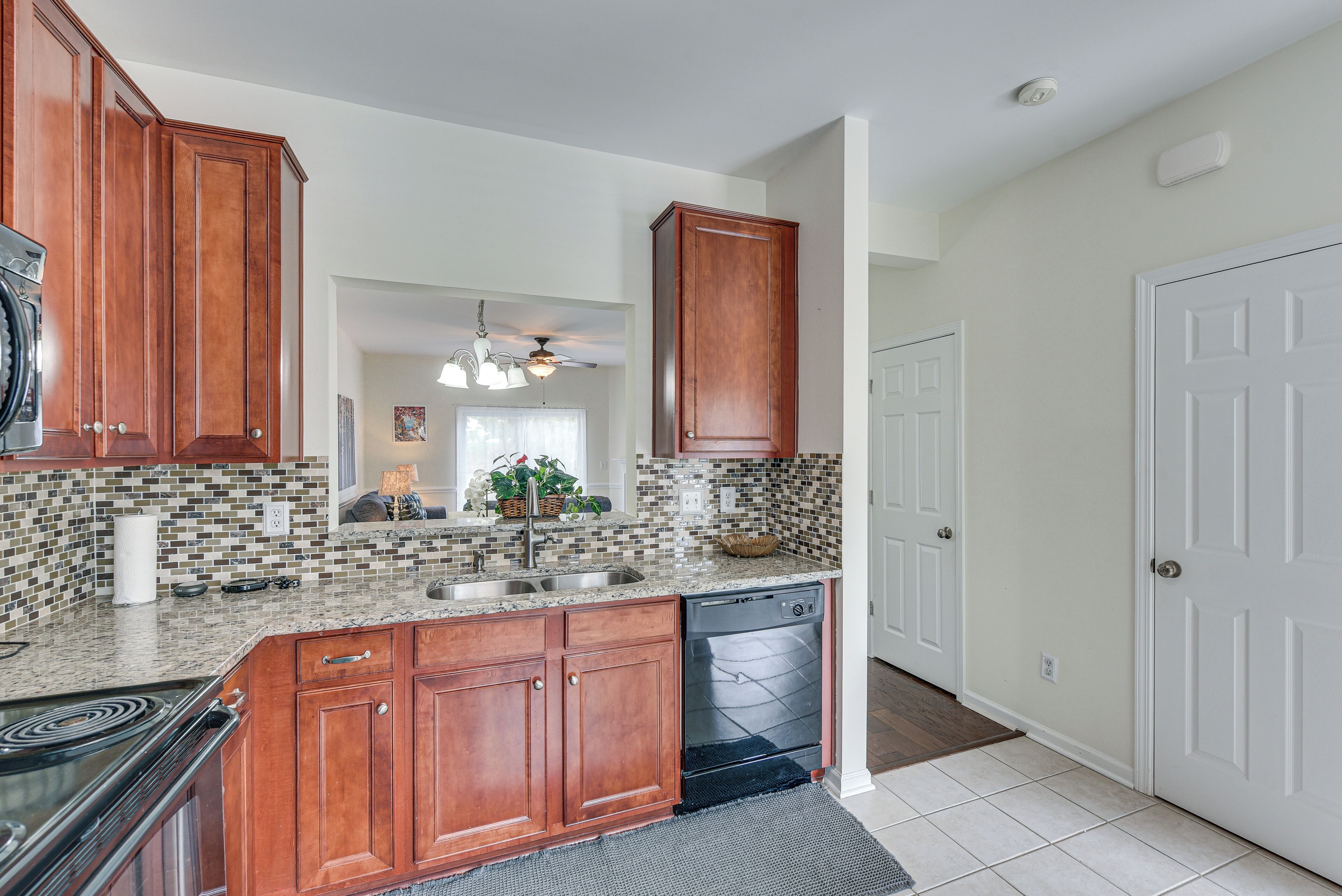 A kitchen with wooden cabinets, a dishwasher, and a tiled backsplash.