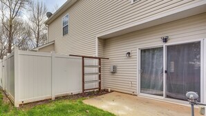 A residential building with a fenced backyard, a sliding glass door, and a satellite dish. - Dog-friendly Townhome w/ Patio in Charlotte Area! (Matthews)