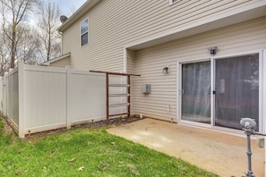 A residential building with a fenced backyard, a sliding glass door, and a satellite dish. - Dog-friendly Townhome w/ Patio in Charlotte Area! (Matthews)