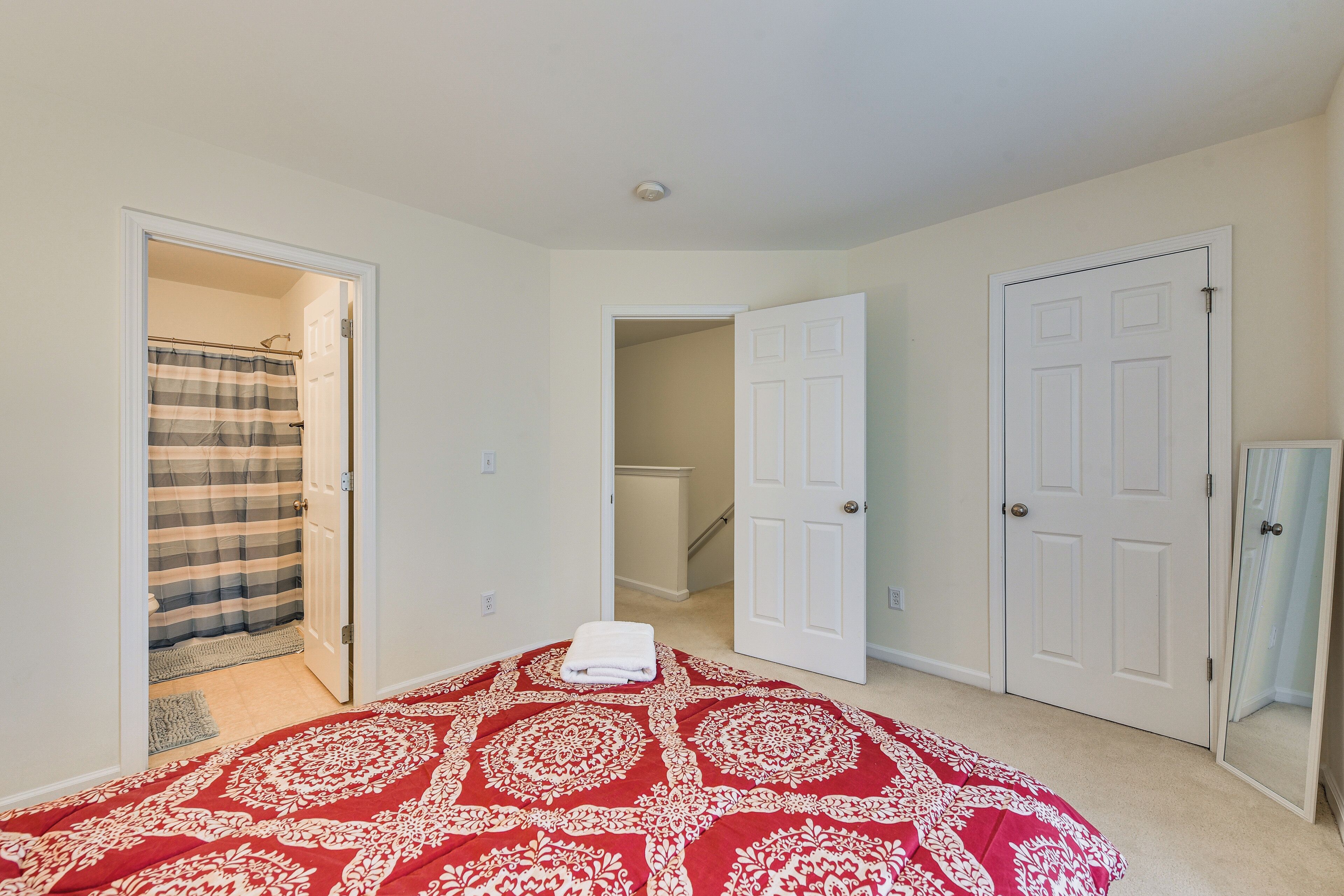 A bedroom with a patterned bedspread, a shower curtain, and two white doors.