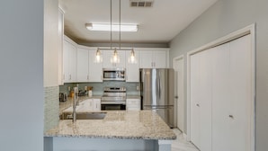 A kitchen with white cabinets, a granite countertop, stainless steel appliances, and pendant lighting. - Pet Friendly! Renovated Arlington Home Near At&t (Arlington)