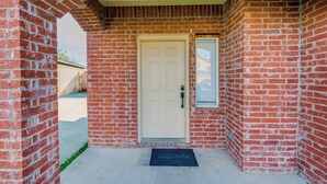 A brick building with a white door, a small window, and a doormat. - Pet Friendly! Renovated Arlington Home Near At&t (Arlington)