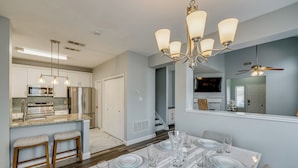 A modern kitchen with stainless steel appliances, a dining area with a marble table set for six, and a ceiling fan. - Pet Friendly! Renovated Arlington Home Near At&t (Arlington)