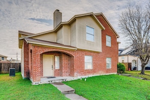 A two-story house with a brick facade, a front door, and a small front yard. - Pet Friendly! Renovated Arlington Home Near At&t (Arlington)