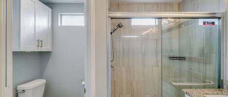 Een badkamer met toilet, douche en douchecabine met glazen wanden.