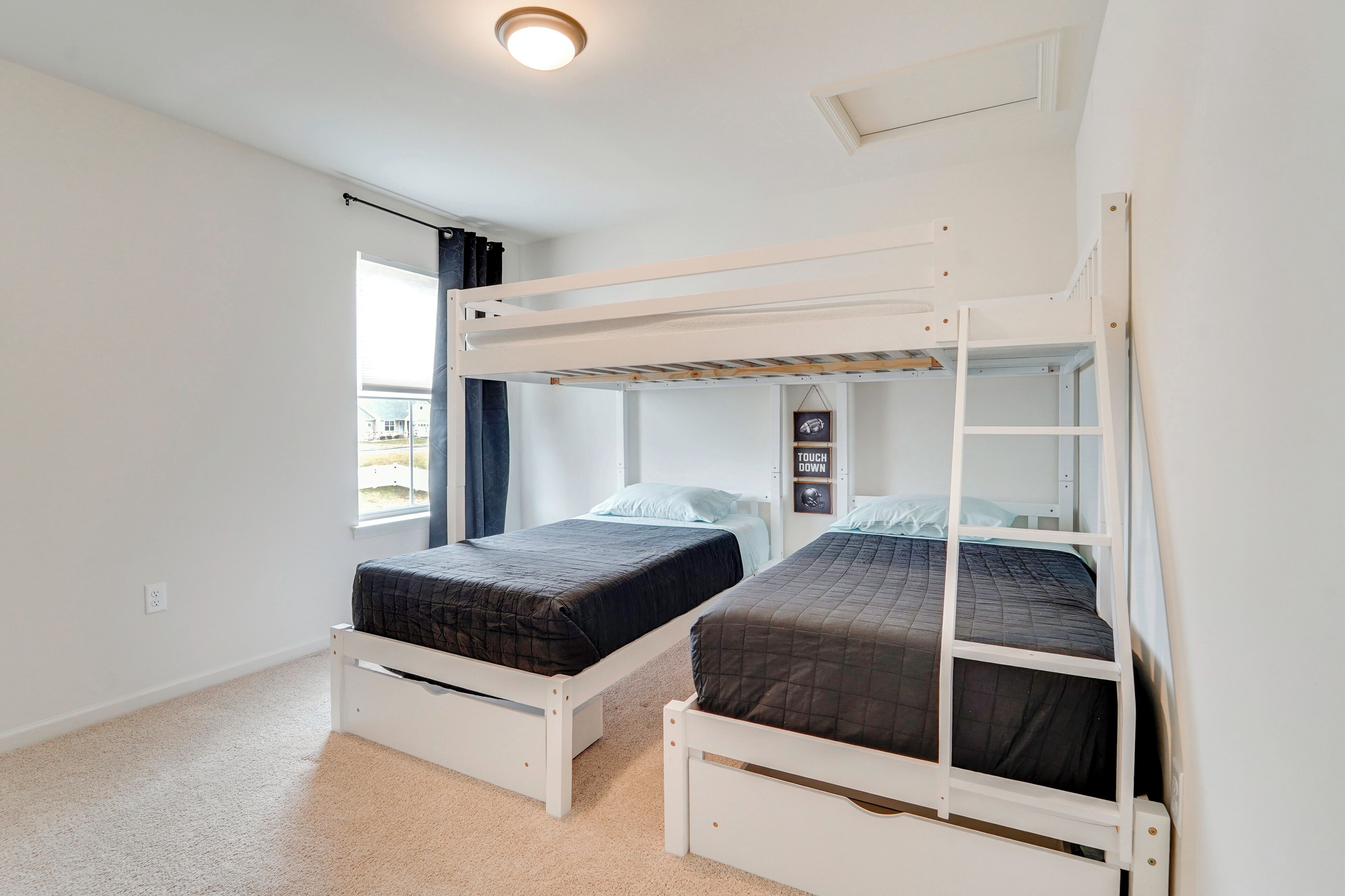 Una habitación con literas, una ventana con cortinas y una lámpara fijada a la pared.