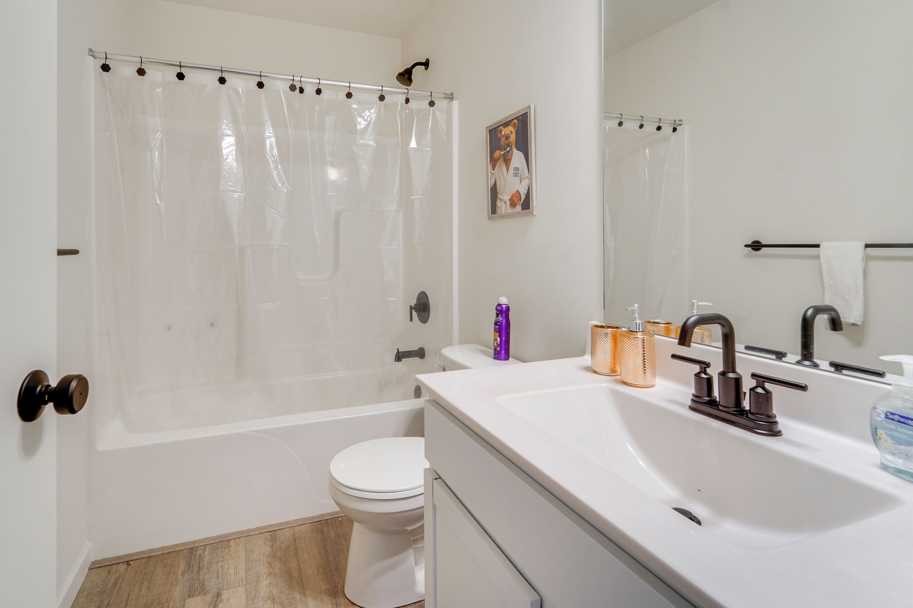 A bathroom with a bathtub, toilet, sink, and a mirror.